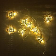 some yellow and white stars are lit up in the dark with string lights on them