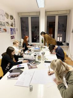 a group of people sitting around a table with papers and pens in front of them