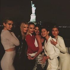 the models are posing for a photo in front of the statue of liberty at night