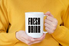 a woman is holding a coffee mug with the words fresh drink on it in black