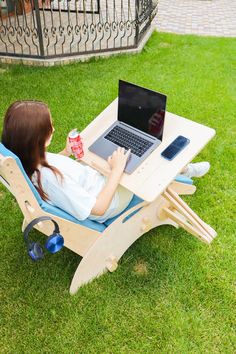 a woman sitting in a lawn chair with a laptop on her lap and holding a drink