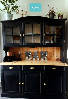 a black hutch with wooden letters and plants in the corner on top of it