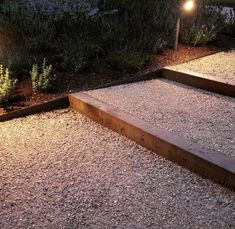 some steps lit up by lights in the garden at night with grass and bushes behind them