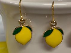 Lemon Gold Enamel Earrings Cute little bright yellow lemon featuring green leaves on top with gold accents. They are single sided with a slightly recessed gold tone back. Gold Plated Surgical Steel Ear wire attached to Gold Enamel Lemon Charm 21mmx13mm Gold Plated Ear wires are Surgical Steel and Brass 20mm 21 Gauge All charm materials Zinc Alloy Metal and Enamel Lemon Earrings, Tone Back, Denim Earrings, Denim Jewelry, Enamel Necklaces, Jewelry Beaded, Earrings Cute, Upcycled Denim, Birthday Jewelry Gift