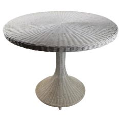 a white wicker table sitting on top of a wooden base with an oval design