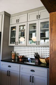 a kitchen with white cabinets and black counter tops, along with lights on the ceiling