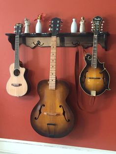 three guitars are hanging on the wall