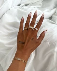 a woman's hand with tattoos on it and two gold rings in front of her