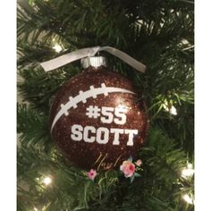 a football ornament hanging on a christmas tree with the number 55 scott written on it