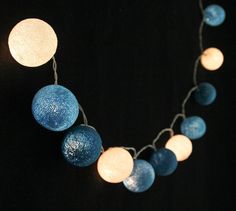 a string of blue and white lights hanging from a black background with circles on it