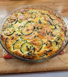 a casserole with zucchini and cheese in a glass dish on a cutting board