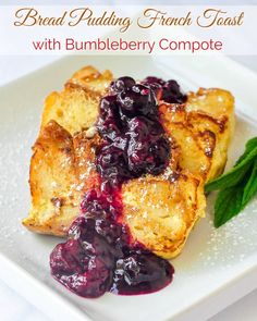 a white plate topped with french toast covered in blueberry compote sauce and green leaves