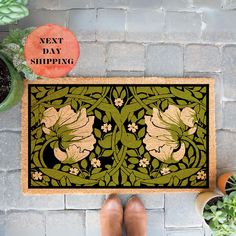 a person standing next to a door mat with an image of flowers and leaves on it