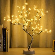 a small tree with lights on it next to some books