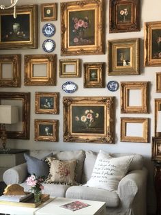 a living room filled with lots of framed pictures on the wall above a white couch