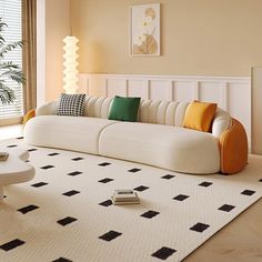 a living room with a white couch and black and orange pillows on the rugs