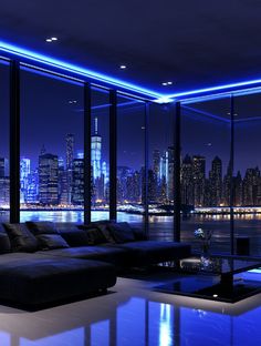 a living room filled with lots of furniture and tall buildings in the background at night