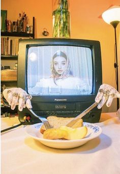 a plate with food on it sitting in front of a television set that is turned on