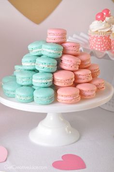 a white cake stand topped with lots of colorful macaroons and cupcakes