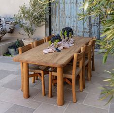 a wooden table sitting on top of a patio next to a planter filled with flowers