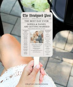 a person holding up a fake newspaper on top of a wooden stick in front of a black chair