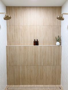 a bathroom with two shower heads and some soap dispensers on the wall