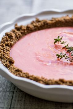 a pie crust topped with crumbs on top of a white plate and garnished with small green sprigs