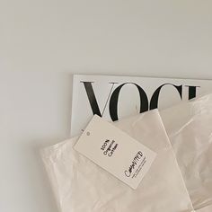 two white bags sitting next to each other on top of a table with a tag