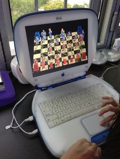 a person using a laptop computer with a chess game on the screen