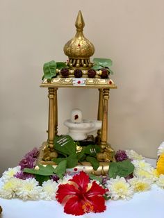 a white table topped with flowers and a gold plate on top of it's stand