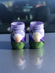 two jars with sea shells in them sitting on a table