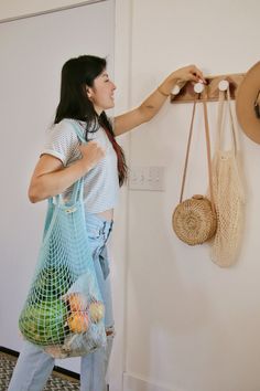 a woman is holding two bags and hanging them on the wall