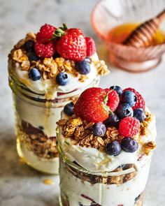 two jars filled with yogurt, granola and berries on top of a table