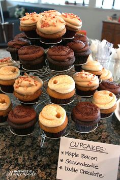 there are many cupcakes on the table and one has a sign that says cupcakes maple bacon