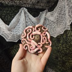 a person holding a piece of art made out of doughnuts with pink icing