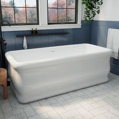 a large white bath tub sitting under two windows