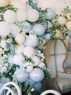 balloons, flowers and greenery are hanging from the ceiling in front of a chair