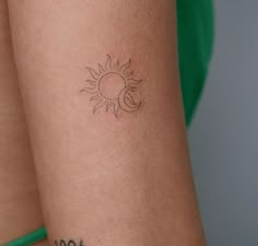 a woman's arm with a small sun and moon tattoo on the left side