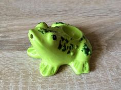 a green frog figurine sitting on top of a wooden table