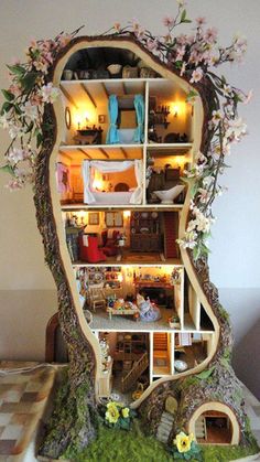 a doll house built into the side of a tree trunk with flowers growing out of it