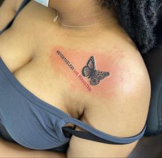 a woman's breast with a butterfly tattoo on her left shoulder and words written below it