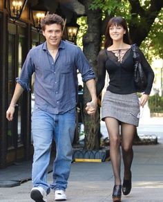 a man and woman walking down the street holding hands