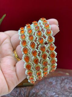 This unique and sophisticated Reverse Polki Sonia bangle is intricately crafted with an orange Polki center and stunning Monalisa stone detailing. Its intricate pearl lining provides unparalleled elegance that will sure to make heads turn. listed as a pair (2 bangles) Pearl Details, Bangles, Turn Ons, Orange, Stone, 10 Things