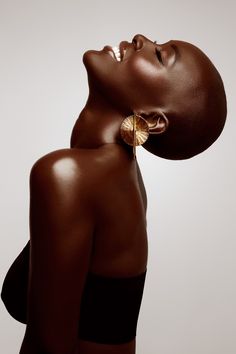 an image of a woman with her head turned to the side, wearing gold earrings