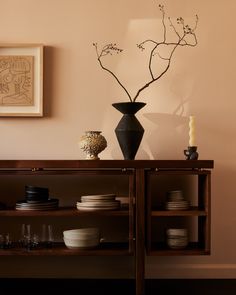 a vase with some flowers in it sitting on a shelf next to plates and cups