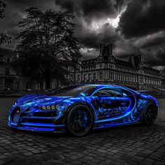 a blue bugatti car parked in front of a building with dark clouds above it