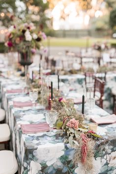 an outdoor table set up with flowers and candles for a wedding reception at the park