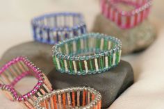 four different colored bracelets sitting on top of a rock