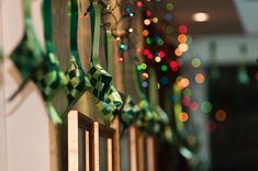 green ribbons hanging from the side of a wooden fence with christmas lights in the background