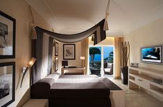 a bedroom with a canopy bed next to a large window and a view of the ocean